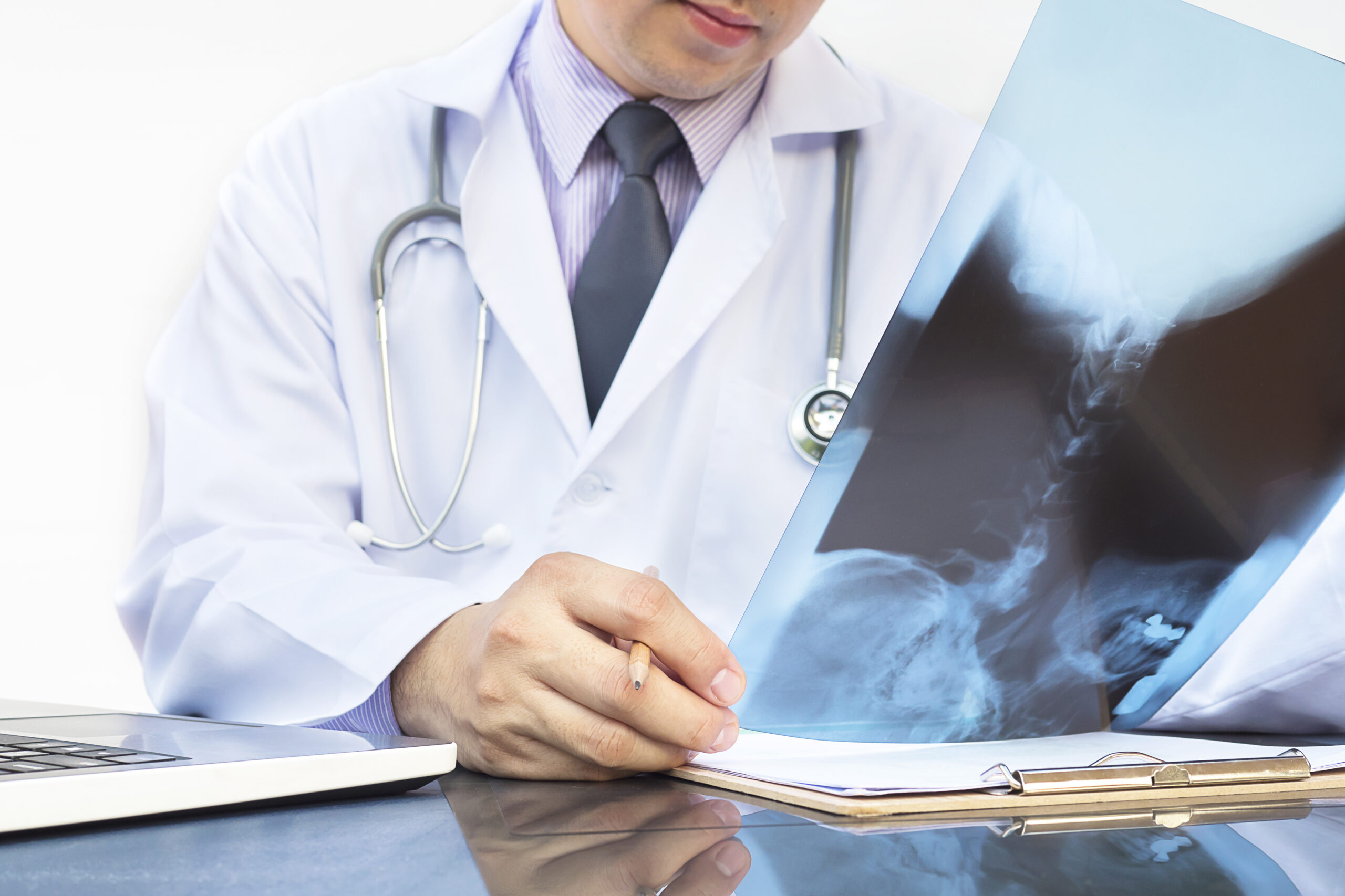 Doctor examine x-ray film over white background Image by jcomp on Freepik